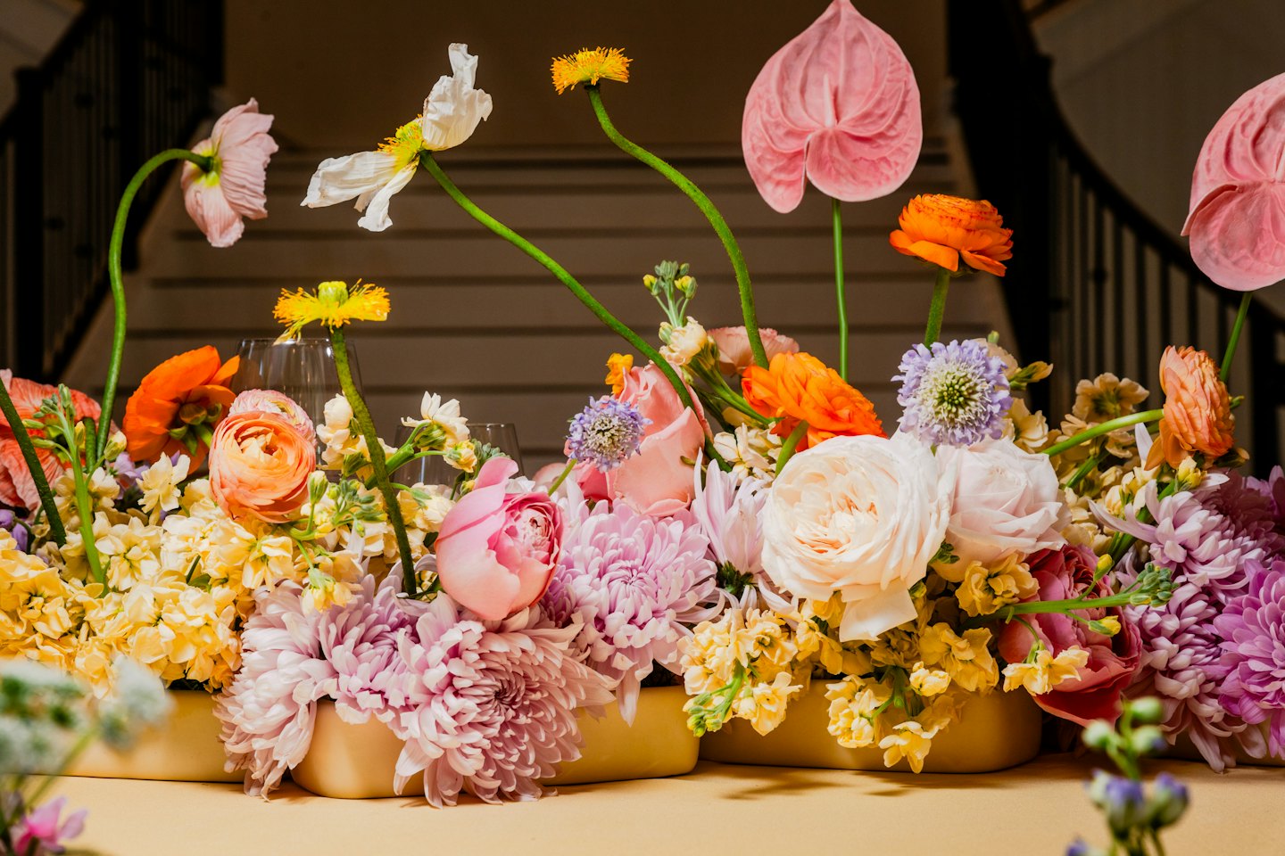 Färgglad blomsterarrangemang med rosor och ranunkler på ett bord.
